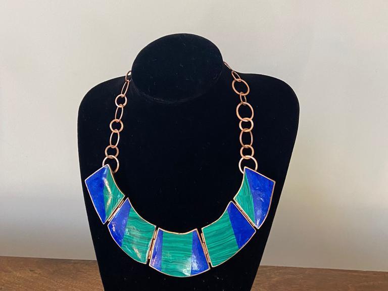 Joyería en cobre, collar en cobre pulido el que tiene figuras cuadradas en notos turquesa y azul. 